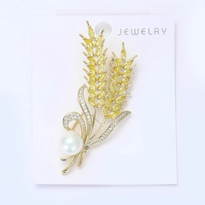 Detail of a gold wheat stalk brooch featuring yellow marquise zircons and a white pearl
