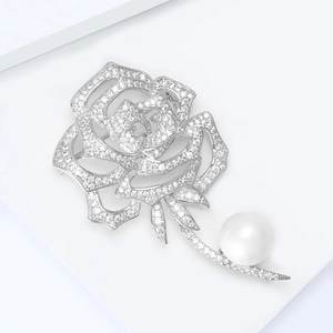 Détail macro d'une broche rose argentée avec micro-cristaux et une perle blanche