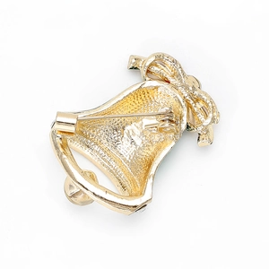 Detail view of the golden metal back and safety pin clasp of a Christmas bell brooch