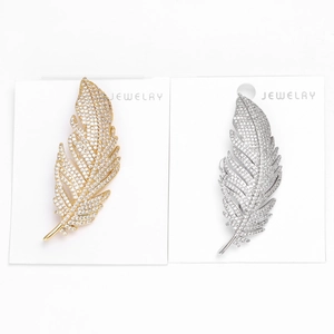 Détail de broches plumes en or et argent avec micro-pavage de cristaux de zircone