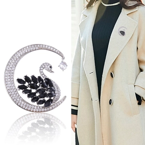 Elegant crescent moon and black swan brooch with crystals on a light wool coat