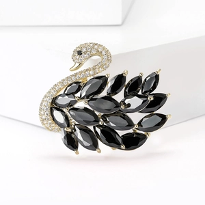 Detalle del broche de cisne en metal dorado con piedras negras y pavé de circonitas