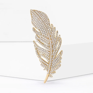 Élégante broche en forme de plume dorée ornée de zircons sur un support minimaliste