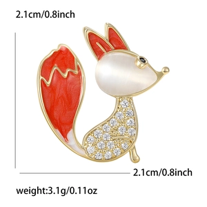 Golden fox brooch with white cat eye stone and red enamel details on a white background