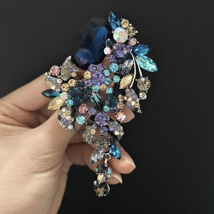 Macro-opname van kleurrijke kristallen bloem-broche met grote blauwe edelsteen en kwastjes