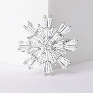Macro shot of silver snowflake brooch featuring baguette and round cut zircons on white cubes