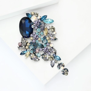 Detail van een luxe vintage broche met donkerblauwe kristallen en stijlvolle kwastjes