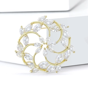 Eleganter goldfarbener floraler Kranz-Brosche mit Zirkonia-Kristallen auf weißem Grund