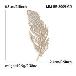 Broche plume dorée avec oxydes de zirconium, dimensions 6,3 cm x 2,4 cm sur fond blanc