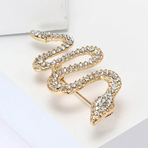 Elegant gold snake brooch with sparkling rhinestones on a white geometric stage