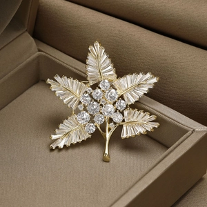 Detailed view of maple leaf brooch with baguette-cut zircons in a premium jewelry box
