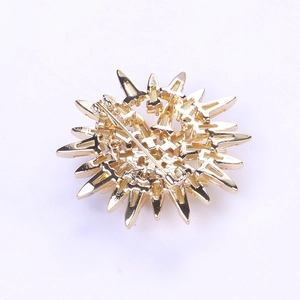 Detail view of the golden snowflake brooch back showing the pin fastener and metallic texture
