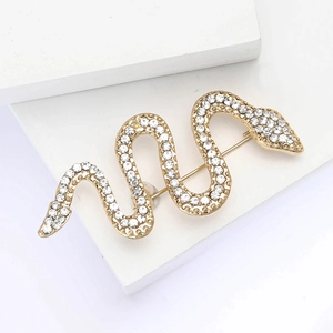 Elegant gold snake brooch with crystal rhinestones on white minimalist background