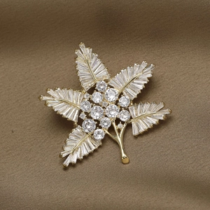 Detailed macro of gold-plated maple leaf brooch with zircon micro-pave setting