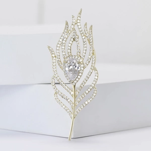Elegant feather brooch with pear-cut stone and pavé gems on a minimalist display