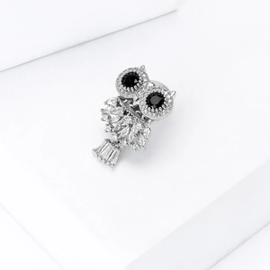 Elegant silver owl brooch with micro-paved zircons on a minimalist white pedestal