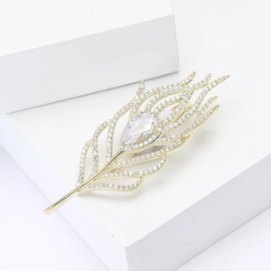 Macro detail of elegant gold feather brooch with pavé zircon stones and a pear-shaped gem