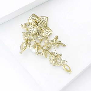 Broche élégante rose dorée avec perles blanches et zircons sur fond blanc épuré