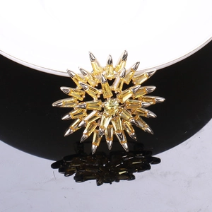 Macro shot of sunburst snowflake brooch with yellow baguette-cut cubic zirconia and silver base