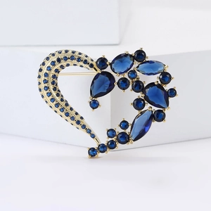 Dettaglio di una spilla a cuore di lusso con base dorata e cristalli blu scuro