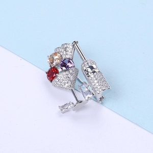 Macro shot of silver cocktail glass brooch with sparkling zircon and colorful gemstones
