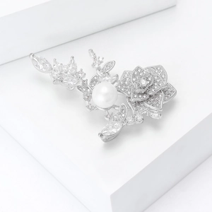 Détail de la broche rose élégante avec cristaux scintillants et perle blanche centrale