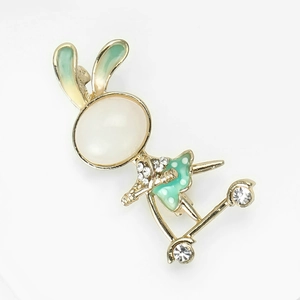 Detail of bunny riding scooter brooch with cat-eye stone and green enamel finish