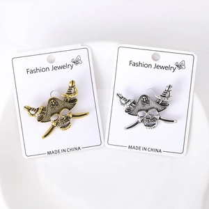 Detailed close-up of retro pirate skull and crossed swords brooches in gold and silver