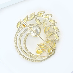 Détail de la broche couronne en cristal doré avec zircons blancs et pierres de feuilles