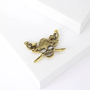 Detailed back view of vintage gold skull and crossbones brooch with pin fastener