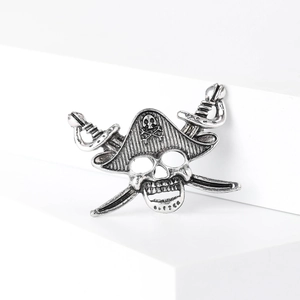 Macro detail of antique silver pirate skull brooch with crossed swords on a white base