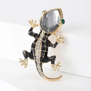 Close-up of lizard brooch featuring gold alloy, black enamel, and sparkling rhinestones