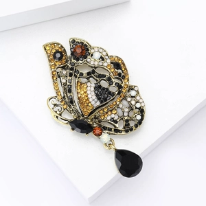 Détail macro d'une broche papillon avec cristaux multicolores et pendentif goutte noire