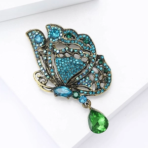 Vue détaillée de la broche papillon vintage avec cristaux bleus et pendentif vert poire