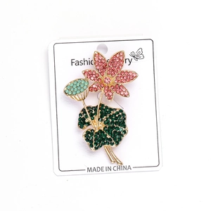 Detail van de lotusbroche met roze en groene strassteentjes op een gouden legering