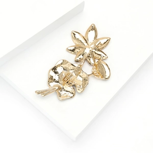 Detailweergave achterkant van de lotusbroche met dubbele veiligheidsspeldsluitingen op goud