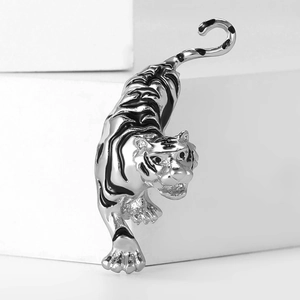 Macro shot of a silver-toned tiger brooch with black enamel stripes on white stone base