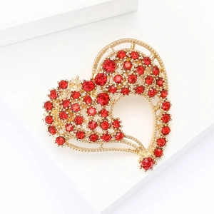 Elegante spilla a cuore traforata dorata con strass rossi su base geometrica