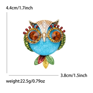 Detail view of owl brooch showing 4.4cm height, blue marble texture, and colorful enamel wings