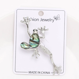 Macro detail of frog brooch featuring iridescent abalone shell and sparkling crystals