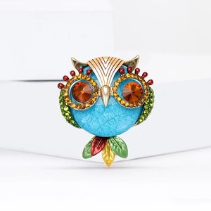 Fashionable owl brooch with blue enamel and sparkling crystals on white background