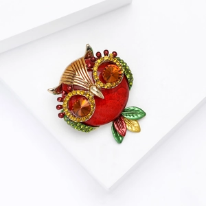 Detailed close-up of crystal owl brooch with colorful enamel on minimalist white background