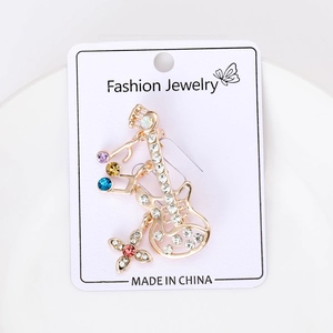 Détail d'une broche guitare dorée avec strass colorés sur une carte de bijoux