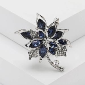 Elegant crystal flower brooch with navy blue petals and silver rhinestones on a white base