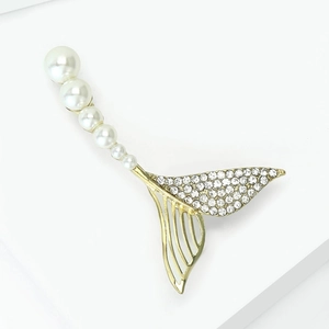 Détail d'une broche sirène en métal doré ornée de strass blancs et de perles dégradées