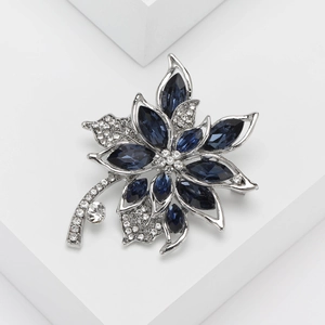 Elegant silver maple leaf brooch with blue crystals and white rhinestones on clean white base