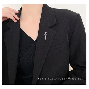 Sparkling silver dagger brooch with white crystals and a red heart gem on a black blazer
