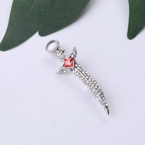 Elegant silver dagger brooch with white crystals, red gemstone and pearl on white background