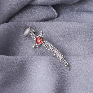 Close-up of gothic dagger brooch with sparkling zircons and a vibrant red center stone