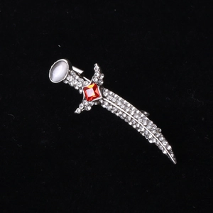 Macro shot of silver dagger brooch with white rhinestones and a red ruby gemstone detail